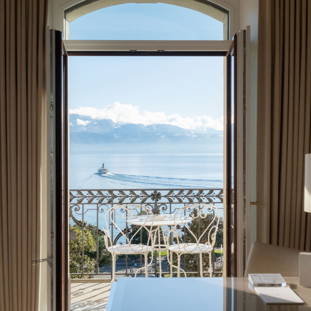 Vue du lac Léman à travers les rideaux d’une suite du Beau-Rivage Palace Lausanne, vue sur le lac et le bateau, avec intérieur luxueux et ambiance élégante, hôtel de luxe à Lausanne et palace 5 étoiles à Lausanne Ouchy pour expérience premium en Suisse