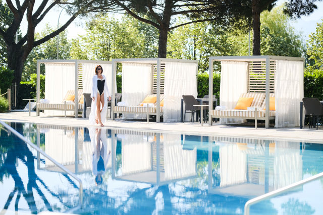 Piscine extérieure du Beau-Rivage Palace Lausanne avec femme admirant le paysage jardins, expérience premium dans un hôtel de luxe à Lausanne et palace 5 étoiles à Lausanne Ouchy